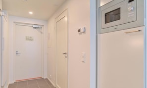A hallway with a microwave oven mounted on the wall, a door with a handle, and a light switch. - Levi Postintie 3B apart.322 by Holiday in Lapland (Levi)
