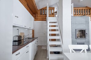 Eine kleine Küche mit weißen Schränken, einer Holzausziehtafel und einem eingebauten Herd.