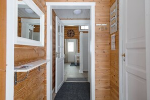 A narrow hallway with wooden walls, a white door on the right, and a white door on the left leading to a room. - Levisalmi A by Holiday in Lapland (Levi)