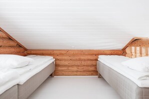 A small, cozy room with two beds, wooden walls, and a sloped ceiling. - Levisalmi A by Holiday in Lapland (Levi)