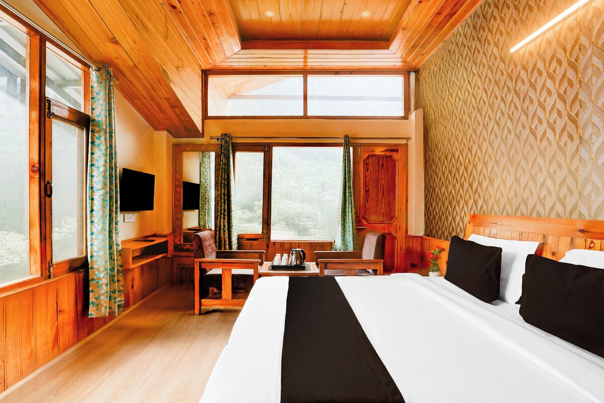Una habitación con una cama grande, muebles de madera, televisión y vistas al exterior.