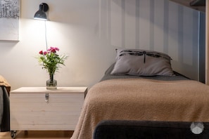Ein Schlafzimmer mit einem Bett, einem Nachttisch, einer Lampe und einer Vase mit Blumen.