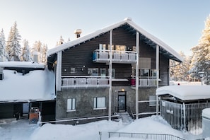 Monikerroksinen rakennus, jossa on parvekkeet, kiviverhous ja lumipeitteinen ympäristö.