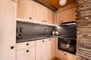 Eine kleine Küche mit Holzausstattung, einem Einbauherd und einer Kaffeemaschine.