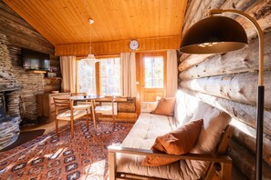 A log cabin interior with a sofa, dining table, chairs, and a large lamp. - Levi Pikkurakka 4A3 by Holiday in Lapland (Levi)