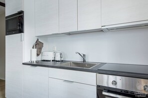A modern kitchen with white cabinetry, a stainless steel sink, a toaster, and a kettle. - Postintie 3A 6101 by Holiday in Lapland (Levi)
