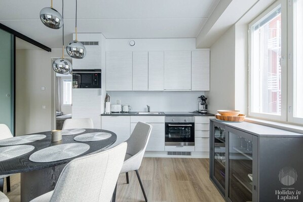 Una cocina moderna con armarios blancos, una mesa de comedor con cubierta negra y una ventana con vistas.