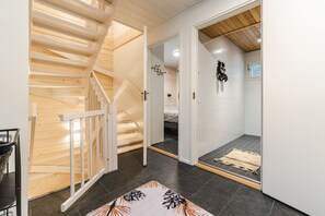Une pièce avec un escalier en bois, un lit et une petite salle de bain où se trouve une serviette sur le sol.