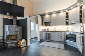 A modern kitchen with a built-in fireplace, stainless steel appliances, and a minimalist design. - Levihovi 6B by Holiday in Lapland (Levi)