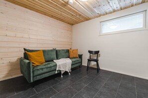 A room with a green sofa, a black chair, a window, and a wooden ceiling. - Levihovi 6B by Holiday in Lapland (Levi)