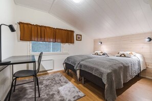 Une petite chambre confortable, avec un bureau, deux lits, une fenêtre avec des rideaux et un radiateur.