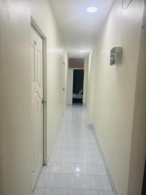 Un pasillo estrecho con una puerta a la izquierda y un interruptor de luz a la derecha.