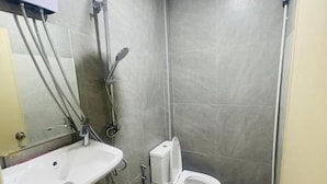 Pieni kylpyhuone, jossa on wc, pesuallas ja suihku.