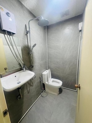 Casa de banho compacta com sanita, lavatório e chuveiro.