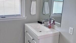 A bathroom with a white vanity, a mirror, and a window with blinds. - Wonderful 3-bedroom house in Fort Wayne perfect for your getaway near downtown (Fort Wayne)