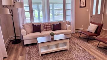Ein Wohnzimmer mit einer Couch, einem Couchtisch, einer Stehlampe, einem Sessel und einem Teppich mit Muster.