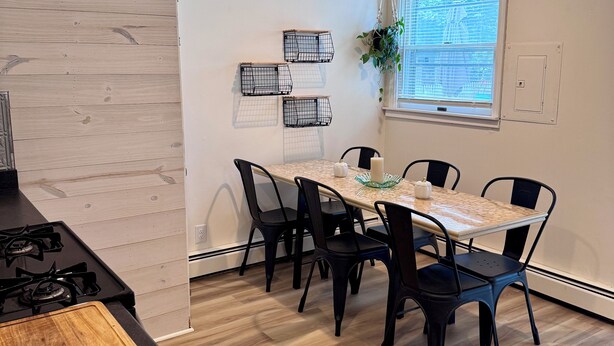 A modern kitchen with a dining area, featuring a wooden countertop, a stove, and a table with chairs. - Wonderful 3-bedroom house in Fort Wayne perfect for your getaway near downtown (Fort Wayne)