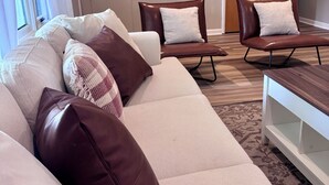 A living room with a sofa, two armchairs, a coffee table, and a door. - Wonderful 3-bedroom house in Fort Wayne perfect for your getaway near downtown (Fort Wayne)