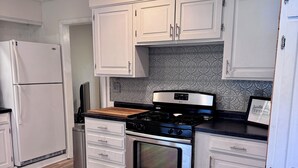 A kitchen with white cabinets, a stainless steel stove, and a tiled backsplash. - Wonderful 3-bedroom house in Fort Wayne perfect for your getaway near downtown (Fort Wayne)