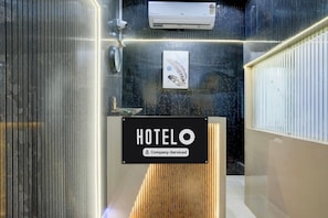 Un espace d’accueil d’hôtel avec une enseigne « HÔTEL », une caméra de surveillance et un appareil de climatisation.