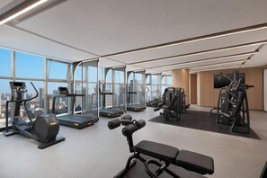 A gym with treadmills, weight machines, and a bench. - Sandalwood Hotel (Hefei)