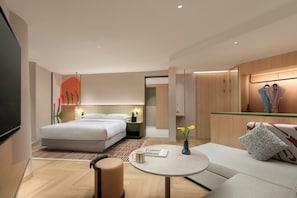 Ein modernes Hotelzimmer mit einem großen Bett, einer Sitzecke mit Tisch und einem Kleiderschrank.