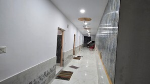 A hallway with white walls, a marble floor, and a red chair.