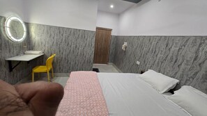 Une chambre d’hôtel avec un lit, une table de chevet, une chaise, un miroir et une porte.