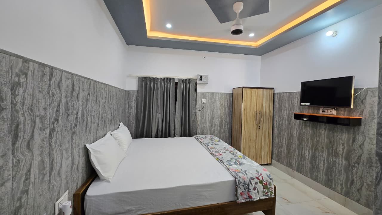 Un dormitorio con cama, televisión, armario y ventilador de techo.