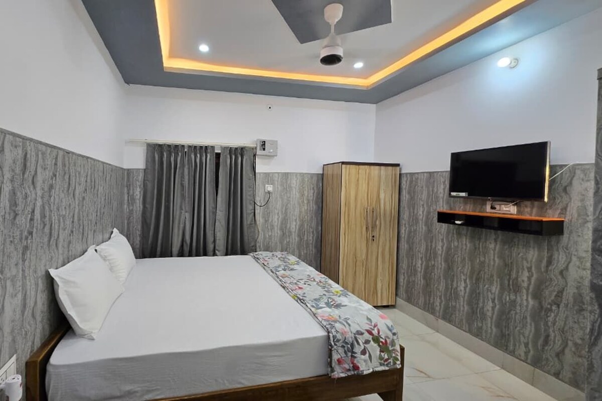 A bedroom with a bed, a television, a wardrobe, and a ceiling fan.