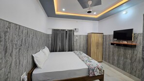A bedroom with a bed, a television, a wardrobe, and a ceiling fan.