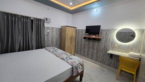 A bedroom with a bed, a wardrobe, a TV, a mirror, and a small table with glasses. - SRM INN (Ayodhya)