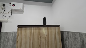 A room with a wooden podium, a projector mounted on the wall, and a grey marble wall. - SRM INN (Ayodhya)