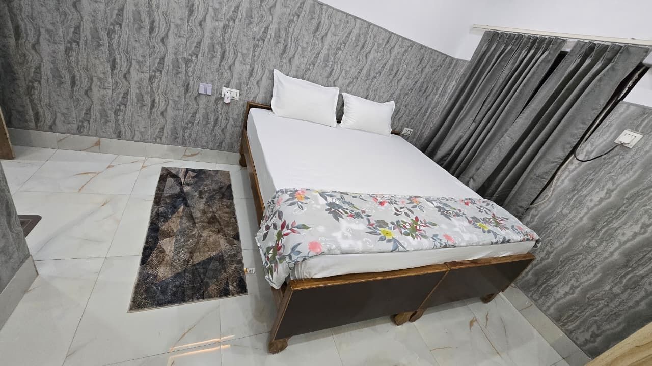 Un dormitorio con cama, alfombra y cortina.