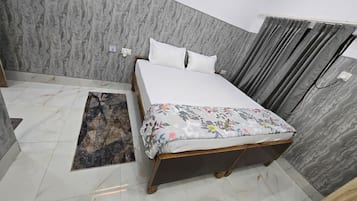 Un dormitorio con cama, alfombra y cortina.