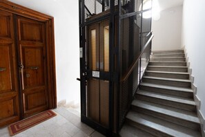 A wooden door, a metal gate, and a staircase with a handrail. - Modern and bright 82-square-meter apartment located on the fifth floor of a building with an elevator (NOT suitable for people with disabilities; there are a few steps to access it). The property is situated in Rome's Ostiense district, in the vicinity o (Rome)