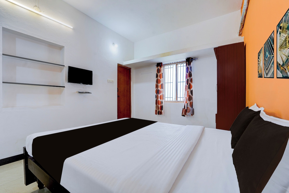 Habitació d'hotel amb un llit, televisió, finestra amb cortines i una estant penjada a la paret.