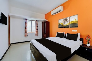 A hotel room with a bed, a window with curtains, an air conditioning unit, and a wall-mounted artwork. - Hotel O SNS Institute Sathy Road (Coimbatore)