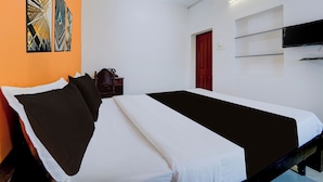 Ein Hotelzimmer mit einem Bett, einem Fernseher, einer roten Tür und einer Wand mit abstrakter Kunst.