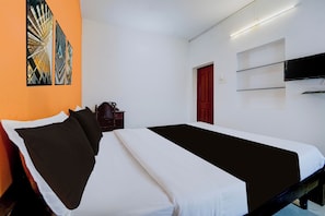 Habitació d'hotel amb un llit, una televisió, una porta vermella i una paret amb art abstracte.