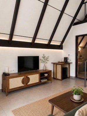 Un salon moderne avec un téléviseur à écran plat posé sur une console en bois, une table basse et une plante en pot.