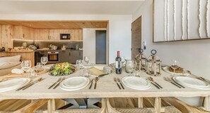 Ein Essbereich mit Holztisch, gedeckter Mahlzeit, einer Küche im Hintergrund und modernem Interieur.