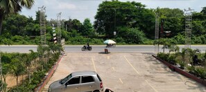 A parking lot with a car, a motorcycle, and a person with an umbrella. - 7 Heaven Hotel & Restro  (Dehari)