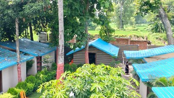 A courtyard with multiple small structures, each with a blue roof, surrounded by lush greenery and trees.