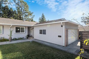 Ein eingeschossiges Haus mit einem Ziegeldach, einer Veranda und einer Garage.