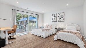Un dormitorio moderno con dos camas, un escritorio y vistas al exterior.