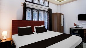A hotel room with a bed, a desk, a TV, and a window with curtains. - Collection O Guwahati Airport (Guwahati)