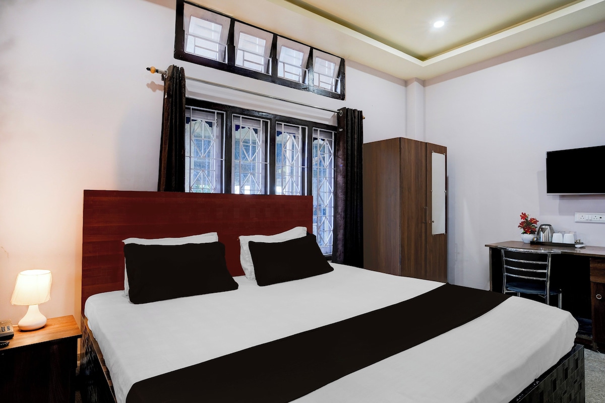 Une chambre d’hôtel avec un lit, un bureau, une télévision et une fenêtre avec des rideaux.