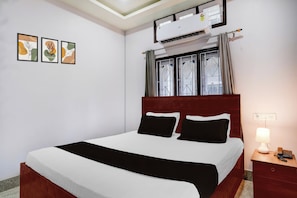 Une chambre d’hôtel équipée d’un lit, d’une table de chevet, d’une lampe et d’un appareil de climatisation.