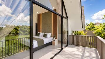 A modern bedroom with a large bed, a bedside table, and a view of greenery through floor-to-ceiling windows.